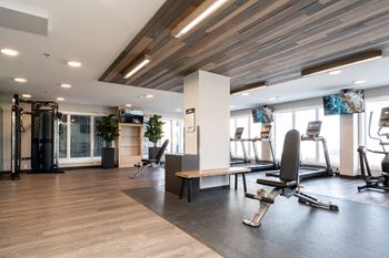 a gym with exercise equipment and chairs in the center of a room